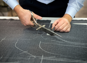 A man skillfully cuts fabric using a pair of sharp scissors, ensuring precise and clean edges.